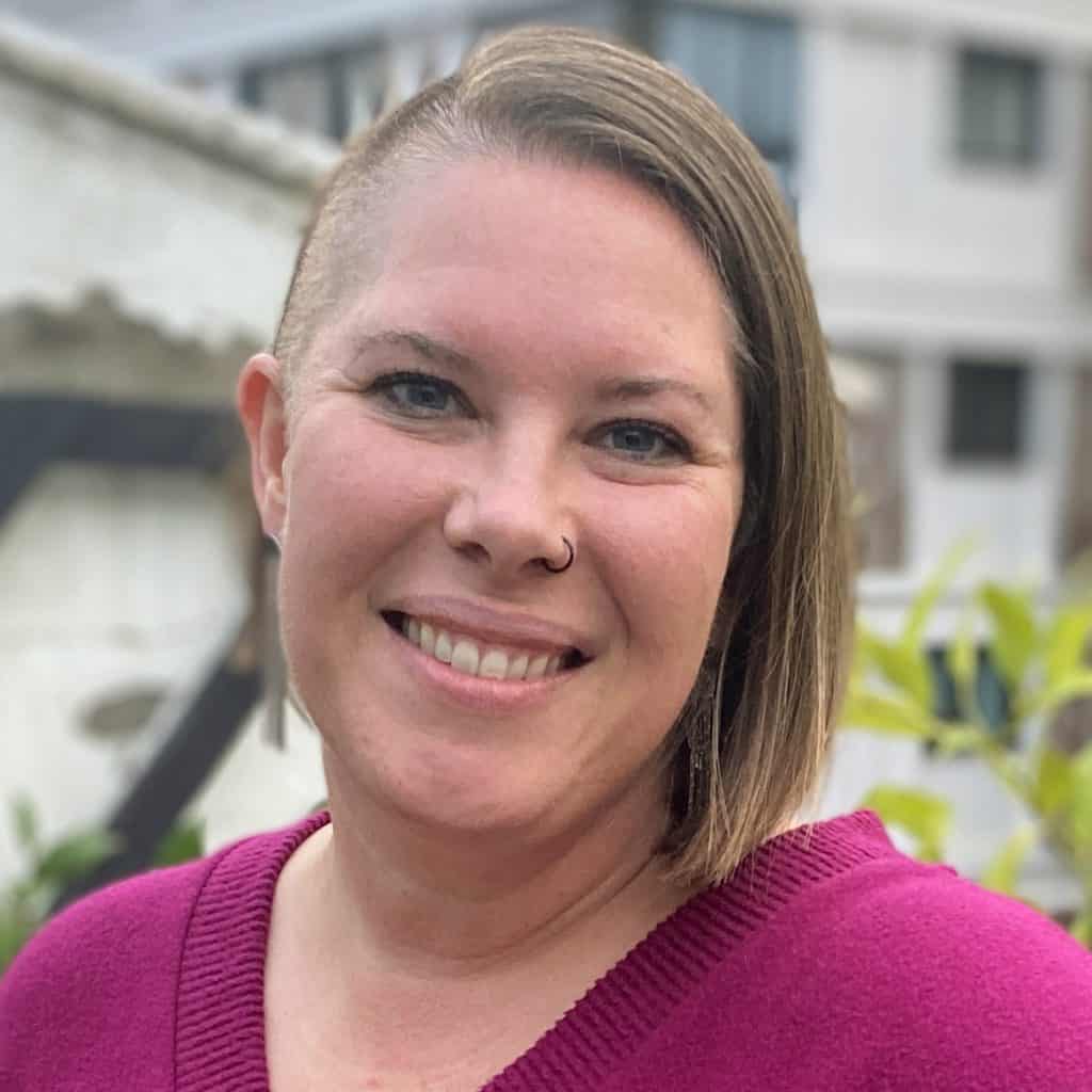 headshot of Kimberly on a balcony wearing a magenta sweater